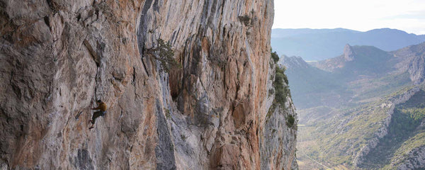 A climber hanging from a rope cleaning hand holds on La Dura Dura, in Oliana, Spain.